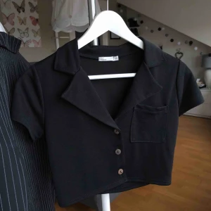  - Svart, kortare topp från NLY TREND (Nelly.com) i storlek XS. Tre knappar i fram men vintage-stuk. Använd EN gång & är i VÄLDIGT fint skick!