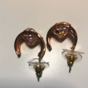 Hoops - Rosé guld örhängen/hoops som har konstgjort diamant bakom. På framsidan är mönstret en ros. Använd en gång endast. Spritas och rengörs innan den skickas iväg. Frakt 11 kr.