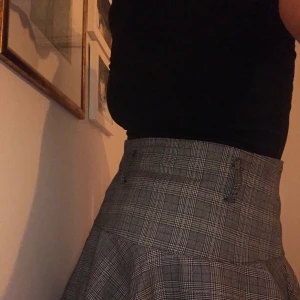 Grårutig kjol - Superfin grårutig kjol! Klockad och väldigt högmidjad med öglor för skärp, slutar över precis över knäna. Köpt vintage. Härlig kvalité på tyget och snyggt fall. För stor för mig (håller bak den lite på bilden, jag är en 38/40, 175cm), har ingen storlek men tror den skulle sitta bra på en 42-46! Gjord i Paris. Knappt använd och i bra skick! [Frakt tillkommer <3]