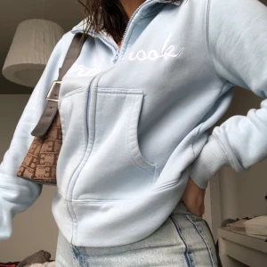 Ljusblå sweatshirt med dragkedja - Ljusblå sweatshirt med dragkedja, broderad text ”North brook”. Tyvärr lite nopprig då den är ganska gammal💕Kan mötas upp i stockholm/köpare står för frakt❤️ 