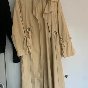 Beige Trenchcoat från MQ i storlek S  - Trendig beige trenchcoat från märket visual clothing i storlek S. Knappt använd då jag köpte den förra hösten. Nyskick. Köpte för 999kr säljer för 450kr. 