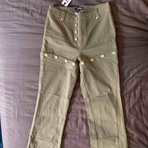 Militärgröna byxor i jeansliknande material med silverdetaljer från I AM GIA. Aldrig använda då de är för stora!  Ord. Pris: 1030kr + frakt och tull (ca 700)