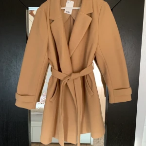 Beige Kappa - Intressekoll på denna helt oanvända kappa från H&M. Vill sälja den för att den tyvärr inte kommer till användning💞 Säljs den står köparen för frakten🥰