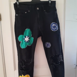 Svarta jeans med patches  - Hej säljer ett par svarta jeans jag sytt på pacthes på och gjort slitna knän 