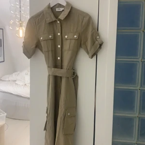 Nakd x Hoss Jumpsuit  - Säljer min jumpsuit från Nakd, Nakd x Hoss, helt oanvänd. Storlek 34, passar även 32-36. Materialet är linnetyg likande i beige/ khaki färg! 
