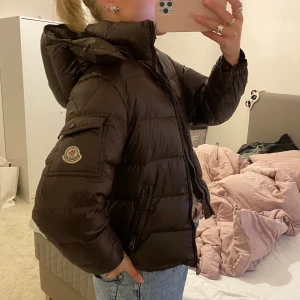 Brun moncler jacka - Brun Moncler dunjacka i modellen maya. Storlek 12, men passar typ som en xs! Superfin men har två mindre  skador, se bild 3 (går fortfarande att öppna som vanligt) och ett igensatt hål som jag kan skicka bild på!