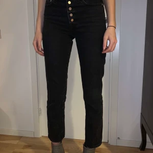 Jeans - Ett par coola vintagejeans med hög midja! På bilden ser ni mig som är 182 cm lång, därför ser jeansen lite korta ut, men det är dem inte. Jag skulle säga att de ändå är i ankellängd. Som ni ser är det ingen gylf utan silverfärgade knappar!