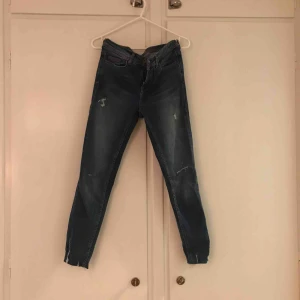  - Stuprörsjeans i ankellängd. Byxorna har slitningar och hål i knäna. Använda men i gott skick. Frakt tillkommer