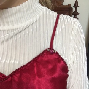  - Skitsnyggt rött silkeslinne!! Egentligen långt nog att vara en klänning men går lätt att stoppa in i byxor (eller bara klippa av) för att kunna användas som linne! :)  Dessutom små tygblommor vid axelbanden, SÅ  snyggt!!