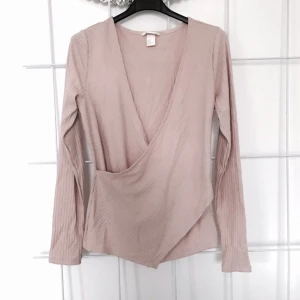  - Ribbad rosa tröja i omlottmodell, endast använd en gång. Kan bäras som ganska tight på en M eller aningen lösare på en S. Kan skicka fler bilder om så önskas! 