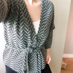  - Kofta från Lindex med knytning i midjan. Koftan är svart och vit, lite vida armar. Aldrig använd, bara testad. Köparen står för frakten 