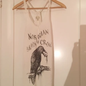  - Vitt Linne med "brottarrygg" och ett motiv av en kråka och text som lyder "norweigan black crow", från carlings