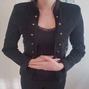  - En svart kavaj med gula knappar i ett bra skick.