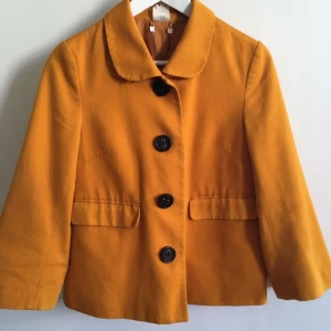  - Senapsgul vid, kort jacka från Monki. Knäpps med stora knappar och har två fickor och trekvartsarmar.  Inköpt för några år sen men sparsamt använd, i gott skick.   Fraktas för 36 kr, kan eventuellt mötas upp i Stockholm.  Jag har swisch och paypal. Vanlig kontoinbetalning funkar också.