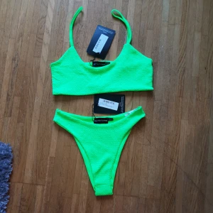  - Limegrön /neongrön bikini.  Topp storlek storlek 38.  Trosa storlek 34.  Köpt från prettylittlething. Färgen är en blandning av bilden jag tagit och bilden från hemsidan.  Halvstring. Refflad tyg. Aldrig använd och skyddet på trosan sitter fortfarande kvar!  Kan träffas upp i Gävle eller posta.   Anledningen till att jag säljer de är pga att jag trodde trosan skulle vara mer string än vad den var (jag gillar helstring). 