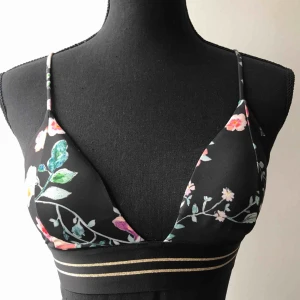  - Blommig bikiniöverdel med guldränder nertill. Vadderade kupor. Använd ett fåtal gånger, som ny i skicket! Köparen står för frakten 🌺