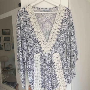  - Helt oanvänd jumpsuit från märket Xenia. Vit/blå med vita spetsdetaljer. Storlek L/UK 12. Nypris ca 400. Hämtas i Malmö alt. står köparen för frakt. Fler bilder: https://www.xeniaboutique.com.au/collections/playsuits/products/snowflake-playsuit-navy-1