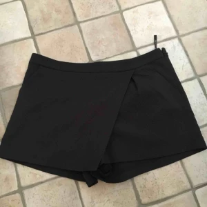  - Shorts i kostymmodell med överhängde ”kjoldetalj”. Osynliga fickor baktill och vanliga sidofickor i fram. Passar 40-42. Köpare står för frakt. 