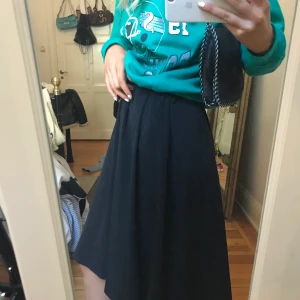 Knälång kjol - En svart kjol med knappar i mitten från Monki. Kjolen går lite längre än knäna och sitter tajt i midjan och har gömda fickor på framsidan. Kjolen är använd ett fåtal gånger och är i mycket bra skick. Nypris=300kr