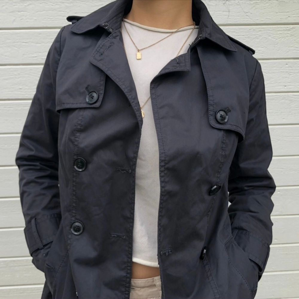 Sparsamt använd trench coat från Banana Republic i mörkgrå. En inneficka, två ytterfickor samt medhörande skärp. Vattenresistent yttermaterial i bomull och polyester. Strl. XS och normal i passformen. Ordinarie pris: 2589 kr. Modellen är 164 cm. . Jackor.