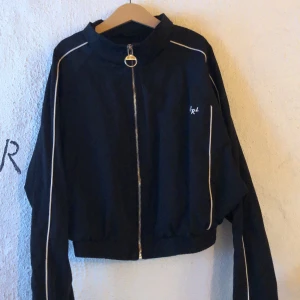 Bershka Windbreaker xs - En svart windbreaker med vita ränder, den är kort så den sitter tajt i midjan. croppad :p