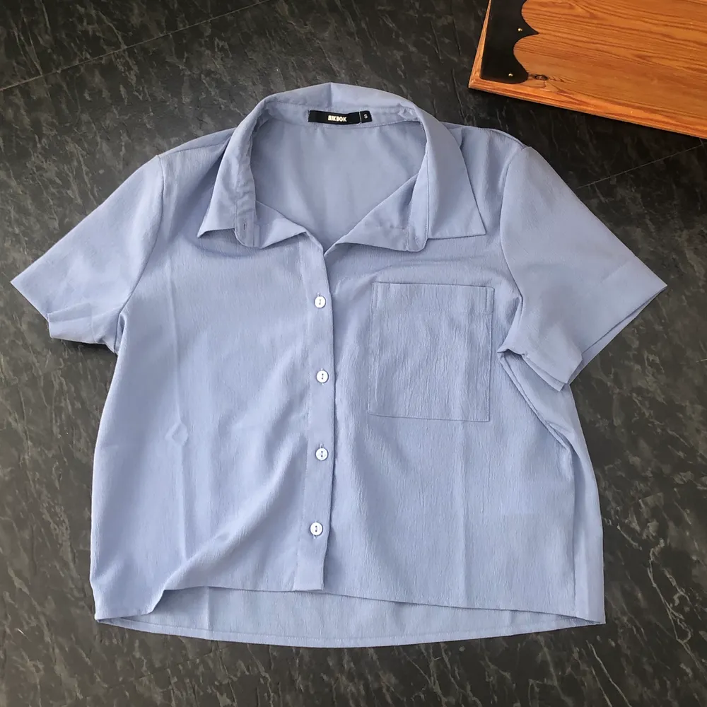 Somrig halv-croppad blå skjorta. Aldrig använd. Tunnt och luftigt tyg. Frakt 20kr, frakten är inkluderat i priset🥰 köparen står alltså för frakten . Blusar.