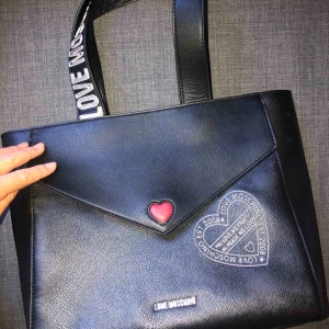 - Jag säljer min jättefina Love Moschino väska då den inte kommer till användning. Endast använd 2 gånger så den är i princip i nyskick. Köpt hos återförsäljare i England för 2500kr. Köpare står för frakt! Kan mötas upp mellan Kungsbacka och Göteborg. Buda