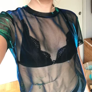 Mesh top från H&M - Snygg mesh top från H&M som skimrar i grönt och blått. Har gått sönder lite men fortfarande supersnygg! Använd några gånger 💕