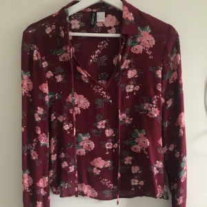 Blus från H&M - Supergullig blommig blus i en vinröd färg! Knytningsdetalj i kragen. Storlek 36🌸 Passar superbra till sommaren då det är ett tunt material! 