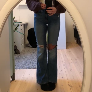 HM Jeans strl 34 - H&M bootcut jeans. Snygga bootcut jeans med slitningar och hål som sitter snyggt. Inte använda många gånger. Frakt ingår ej.