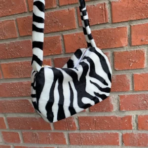 Zebra väska  - Jättesnygg egensydd väska med blixtlås som jag köpte här på plick i somras. Hon som sydde väskan strykte även in ett fodral för att göra den mer stabil. Säljer för att den tyvärr inte kommer till användning längre❤️❤️ Ifall flera bilder önskas kontakta mig!