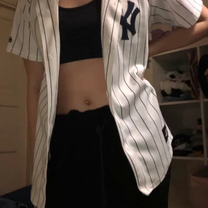 Button up shirt  - Button up shirt som påminner om en baskettröja. Den har en tvåa på ryggen och ett new york märke på bröstet. Frakten ingår i priset 