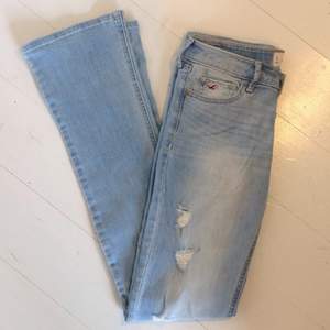Ljusblå utsvängda bootcut-jeans från Hollister med små trasiga slitningar på benen. Super stretchiga och sköna att ha på sig, låg midja! Storlek 3L (långa ben)