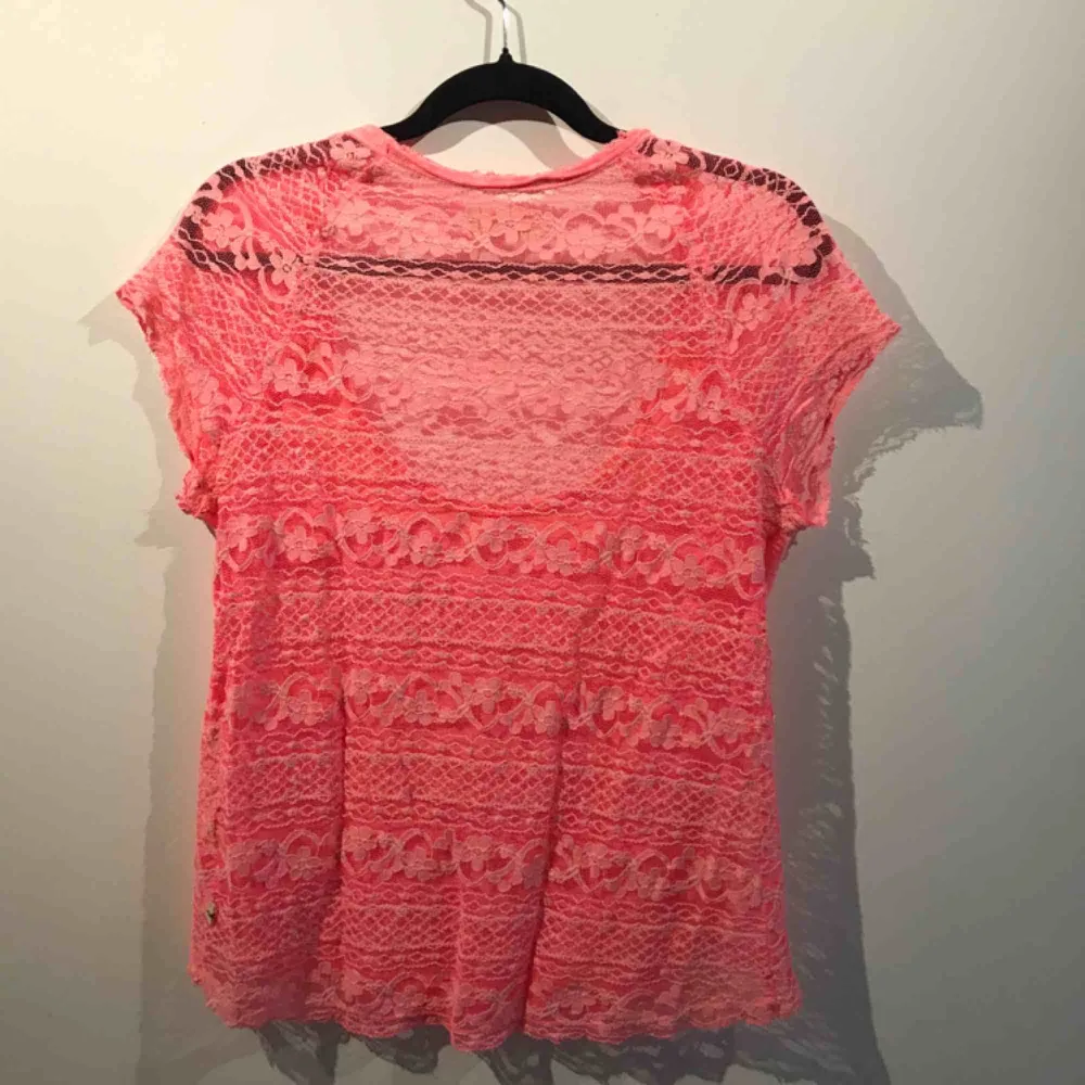 Säljer en rosa t-shirt med spets i ryggen från Hollister, i storlek L. Priset är med frakt inräknat. T-shirts.