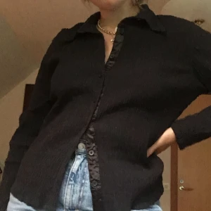 Svart 90-tals topp/skjorta - Snygg 90-tals topp i skjortformat. Den är i väldigt snyggt skick, och har snygga detaljer och passform. Toppen är stretchig och tyget är skrynkligt (på ett snyggt sätt :))”