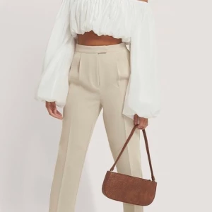 Figursydda, Croppade Kostymbyxor - Superfina beiga kostymbyxor från NA-KD. Storlek 32 men är som 34. Helt oanvända (prislapp kvar)💗 köparen står för frakten. Nypris 499kr ( lånad bild från na-kd hemsida)