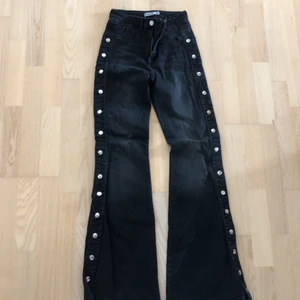 NA-KD byxor  - Ett par svarta bootcut byxor med silvriga knappar längs benen. Använda 2 gånger. 