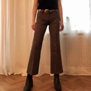  - Utsvängd byxa i brunt med smala beiga ränder. Material: bomullsblandning. Stlk. S, normallängd. Köparen står för frakt, kan även mötas upp!