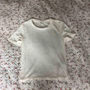  - Vit lite finare t-shirt i räfflat tyg. Från Monki. Tunnare material, perfekt för sommaren. Krämig vit. Passar S och M. Frakt tillkommer.