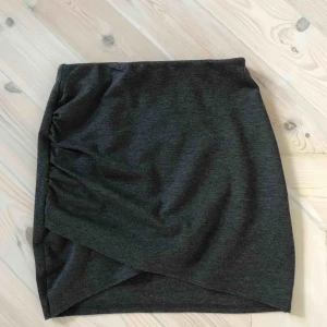  - Snygg mörkgrå kort kjol. Den går omlott och den sitter väldigt fint! Fin till fest och vardag🥰 Resår i midjan och mjukt material=väldigt skön! Knappt använd. 