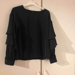  - En svart volang tröja. Aldrig använd 