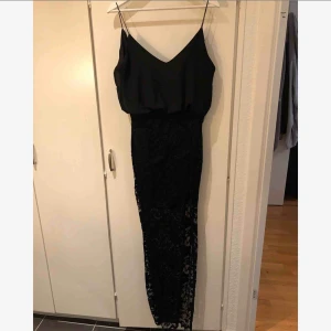  - Jätte fin svart lång klänning. Spets hela nederdelen med slits. Smala axelband. Försluts med dragkedja och knapp där bak. Knappt använd 😊
