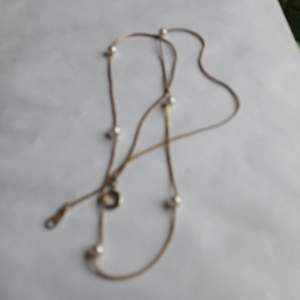 litet fint halsband med silver med små vita pärlor.litet fodral rött som hör till för vara halsband i.