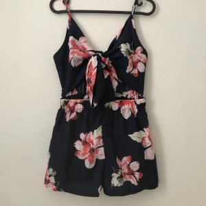 Jumpsuit från ZAFUL - En fin mörkblå jumpsuit med knytning och öppen mage. Från Zaful men aldrig fått användning av den och därför säljer jag den. Färgerna syns inte så bra på bilderna men blommorna är rosa och bladen gröna. 150kr och frakten ingår i priset (tar bara swish)
