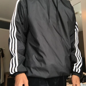 Adidas windbreaker/prasseljacka - Tunn adidas jacka med logga på ryggen. Säljer då den är för stor för mig. Storlek S men sitter som M/L. Pris kan diskuteras, budgivning om fler är intresserade, frakt tillkomm