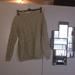  - Stickad kabeltröja i storlek 36. 
Vit/ljus-beige i färgen.
 Av 100% bomull. 