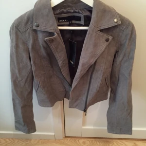 - Oanvänd grå bikermodell-jacka i mockaimitation från Zoul. Nypris 500kr. 