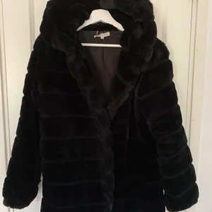 Pälsjcka - En len och mjuk fake päls jacka med luva. Har dock inga knappar eller dragkedja.😊