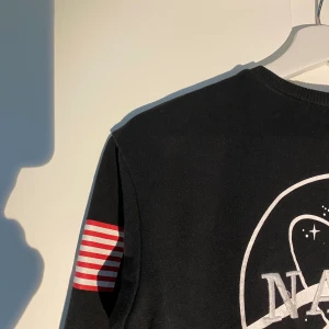 NASA sweatshirt - sweatshirt med NASA logga. Bra skick utöver några lösa trådar på den sydda texten - men kan fixas innan den skickas iväg. (Frakt går att göra spårbar).