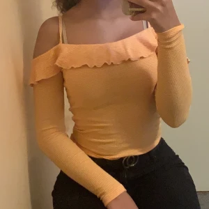 Gul Och vit sort of off shoulders tröja - Nästan en off shoulders tröja, har två stringar som håller uppe tröjan. Fin gul Och vit kombination.